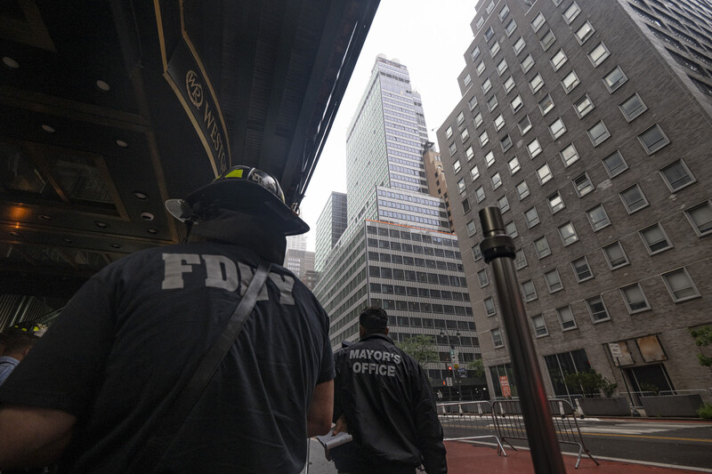 Street-level urban photography showing pedestrians and downtown skyscrapers with Mayor's Office signage