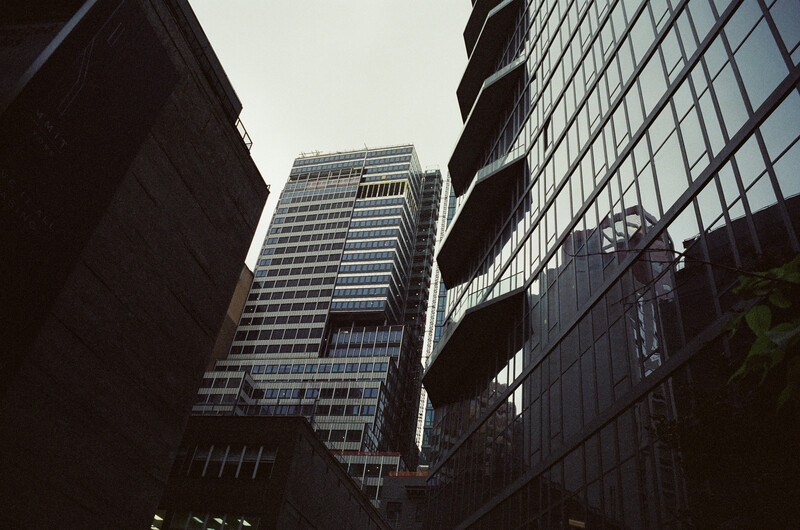 Urban canyon perspective of modern skyscrapers framed by darker office buildings