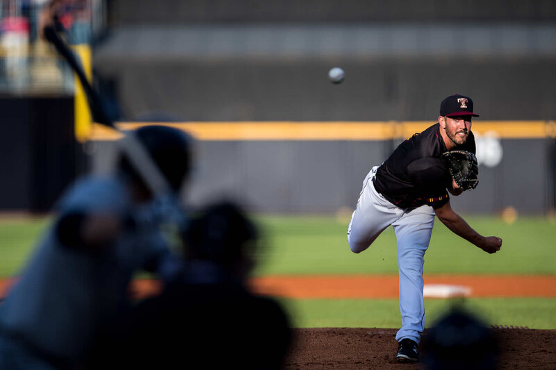 Baseball pitcher mid-delivery throwing from the mound with catcher in foreground