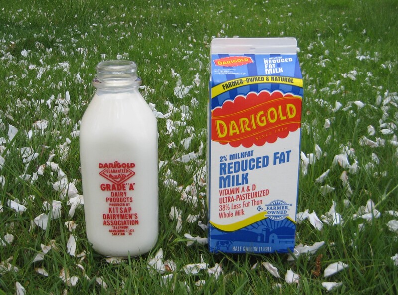 A US half-gallon gable-top paper milk carton beside a quarter-gallon glass milk bottle from 1956