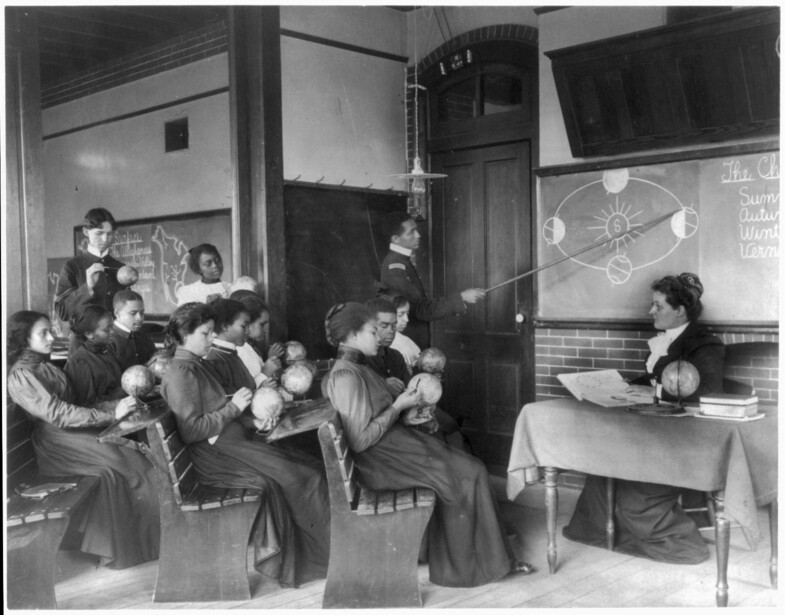 A class in mathematical geography at the Hampton Normal and Agricultural Institute in Virginia studies the earth's rotation around the sun, from Frances Benjamin Johnston's Hampton Album of 1899 to 1900