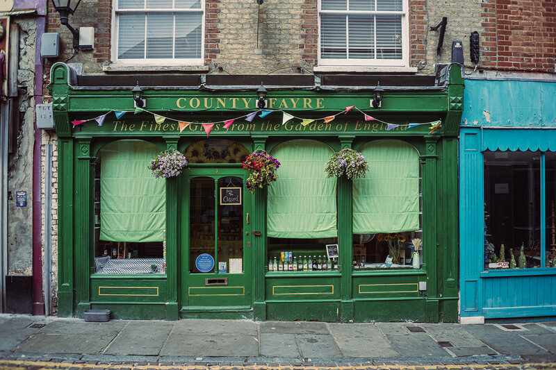 Historic green storefront with hanging flower baskets and traditional Victorian architecture