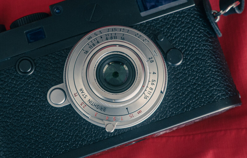 Vintage rangefinder camera with fixed lens on red background
