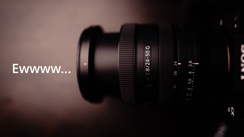 Close-up of a telephoto lens showing focal length markings and focus ring against blurred background