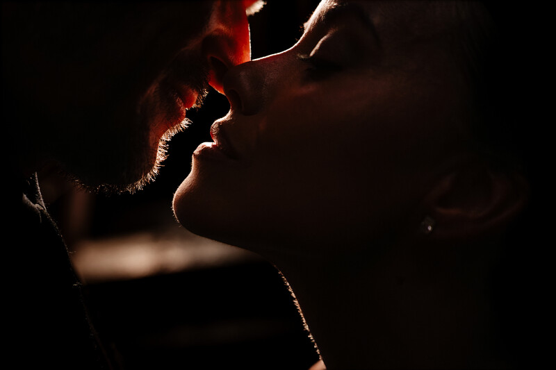 Profile of person's face illuminated by warm rim lighting against dark background