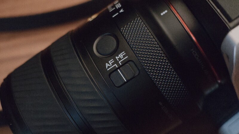 Close-up of camera lens control ring showing AF/MF autofocus toggle and manual focus adjustment buttons