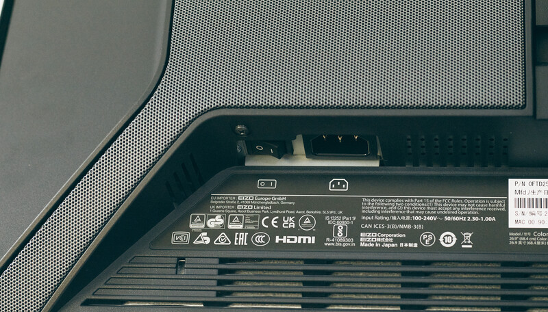 Close-up of monitor rear panel showing ports, vents, and regulatory certification markings
