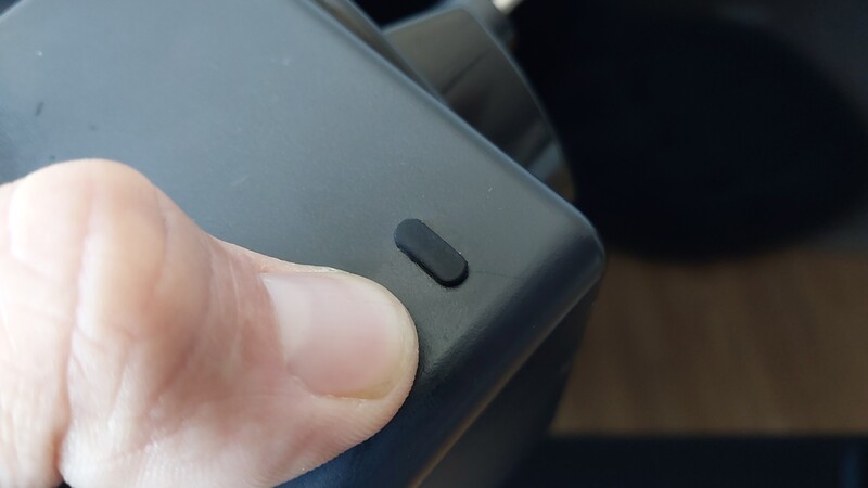 Close-up of a finger pressing a small black button on a dark device