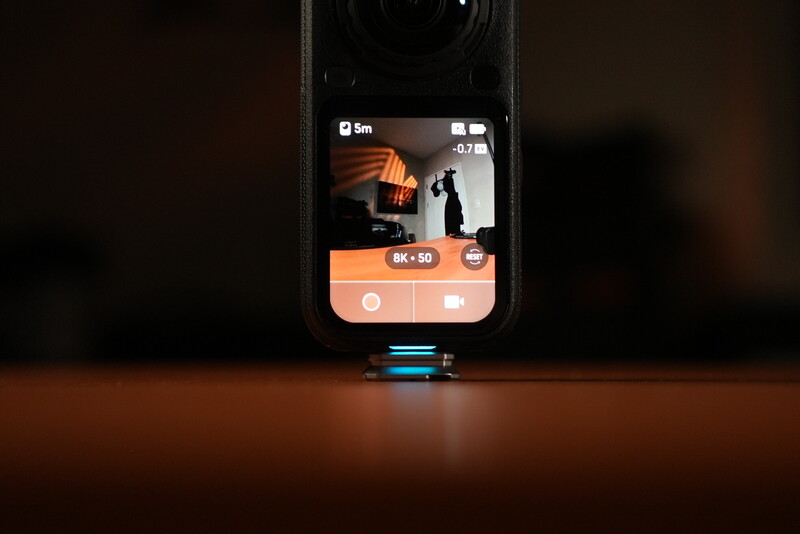 Smartphone mounted on compact gimbal displaying video recording interface with orange UI elements