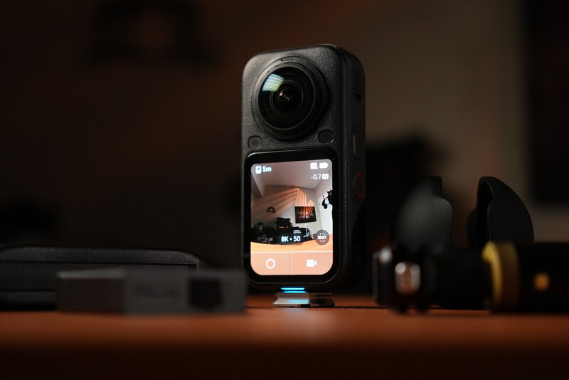 Insta360 One RS action camera with flip-out touchscreen displayed on wooden surface