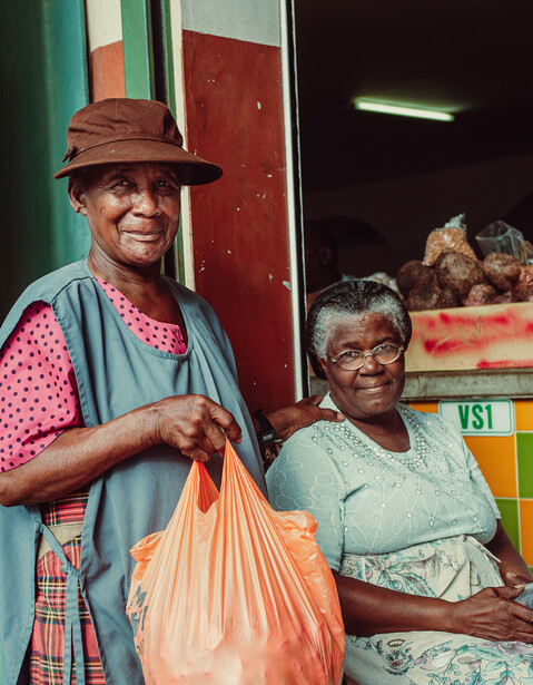 Two smiling women standing in a doorway with colorful building exterior behind them