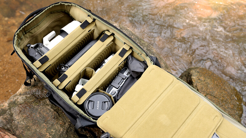 Open camera bag with organized gear compartments containing lenses and photography equipment