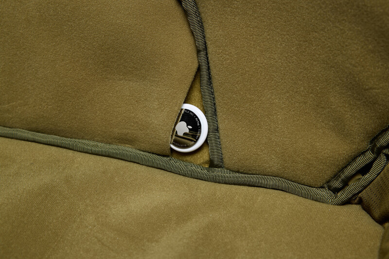 Close-up of tan fabric with gray webbing straps and metal D-ring attachment