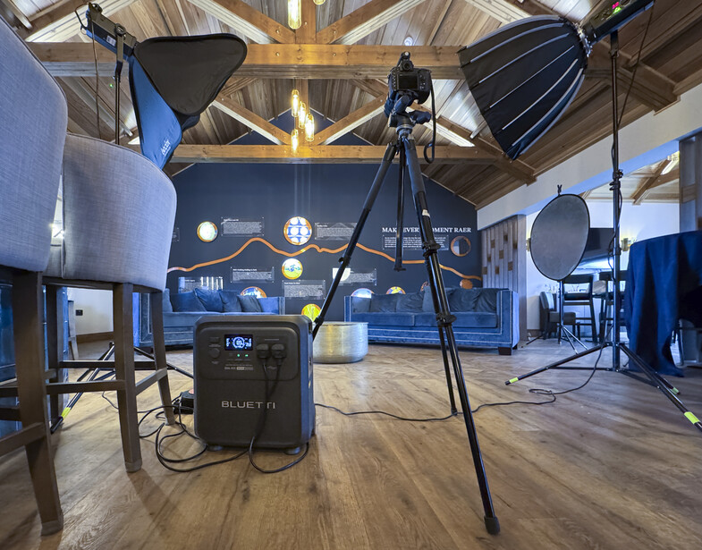 Professional photography studio setup with softbox lighting rigs, tripods, and power equipment on wooden floor
