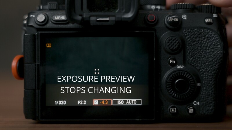 Screenshot of mirrorless camera rear LCD displaying exposure preview freeze notification with exposure settings visible