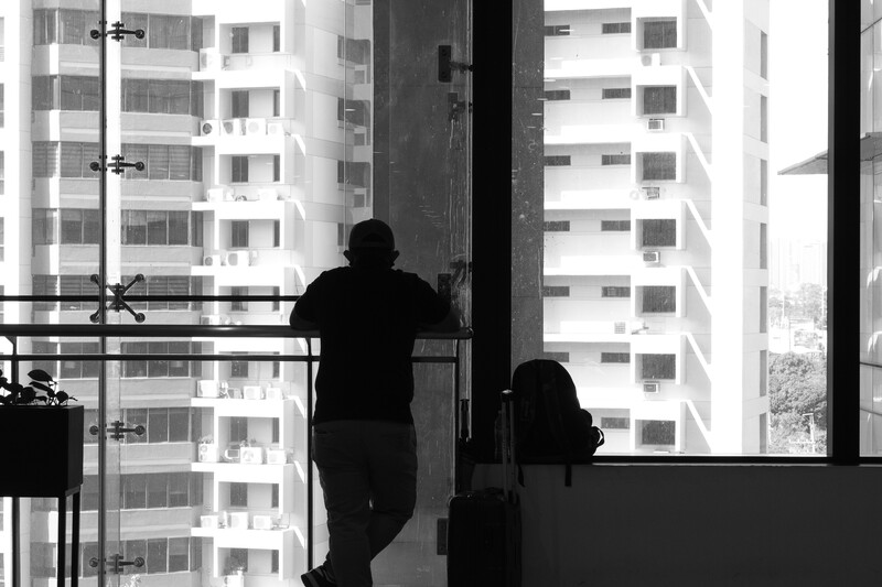 Silhouetted figures on a high-rise balcony overlooking repetitive apartment buildings