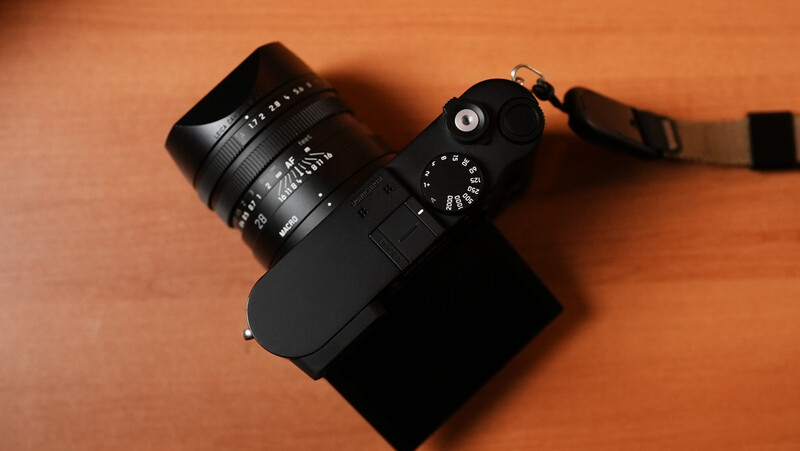 Black rangefinder camera with mounted wide-angle lens on orange background