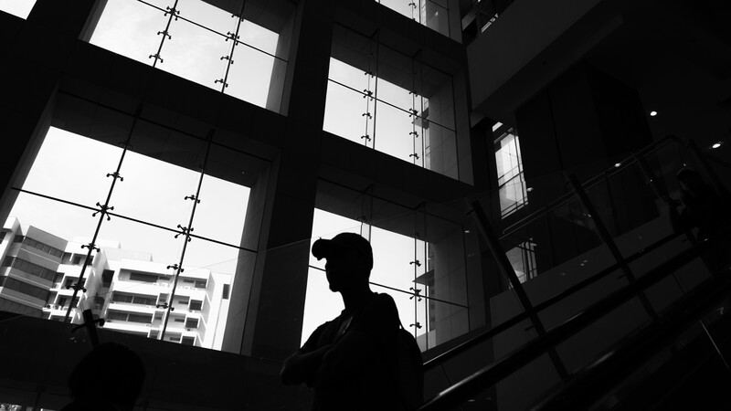 Silhouetted figure against large gridded windows with city buildings visible outside