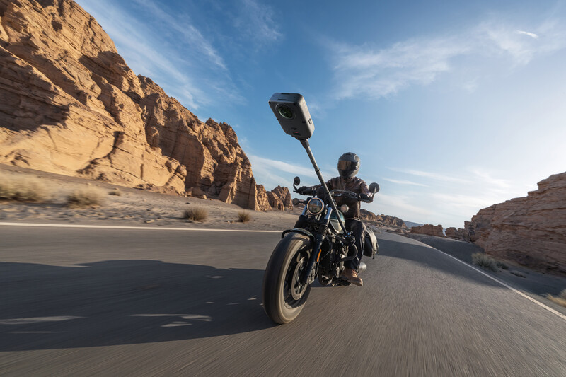 Motorcyclist riding cruiser on desert highway with towering red rock canyon walls