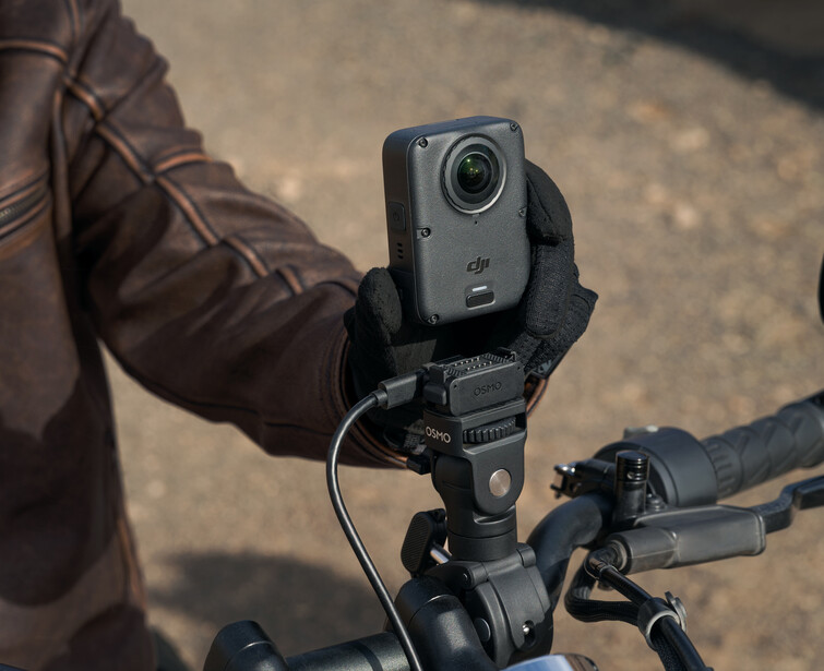 Filmmaker holding a compact camera stabilizer mounted on bicycle handlebars