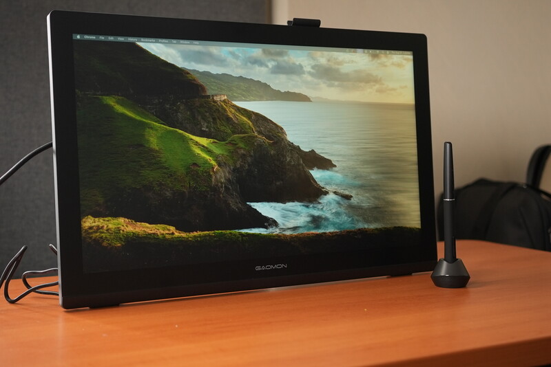 Portable monitor displaying coastal landscape with green cliffs and ocean