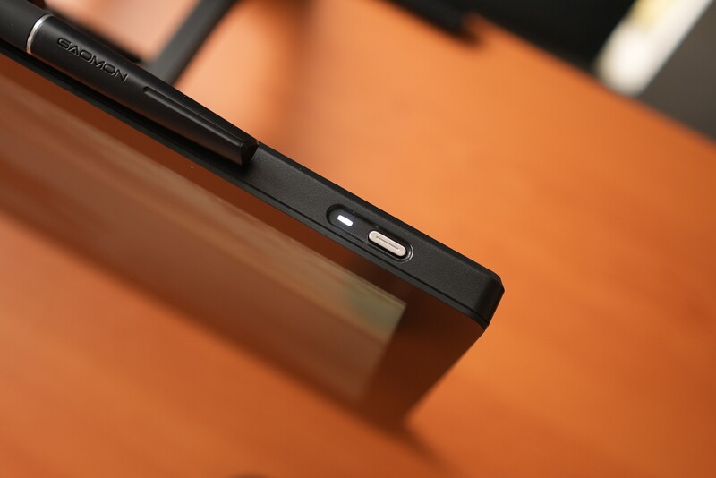 Black stylus pen resting on tablet device against warm orange background