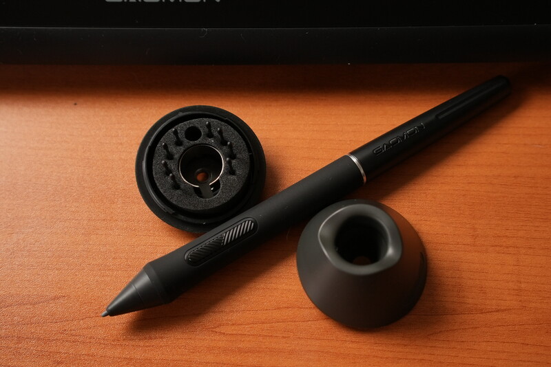 Black stylus pen with detachable components and charging dock on orange wood surface