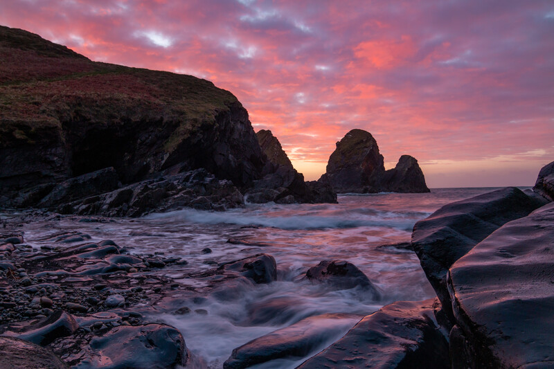 Rocky coastline at sunset with sea stacks and long-exposure ocean waves