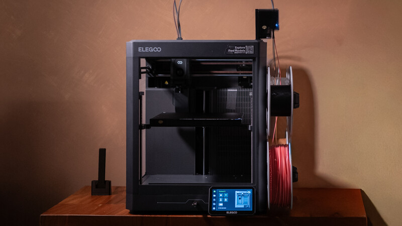 Elegoo 3D printer with open chamber and control panel displayed on wooden surface