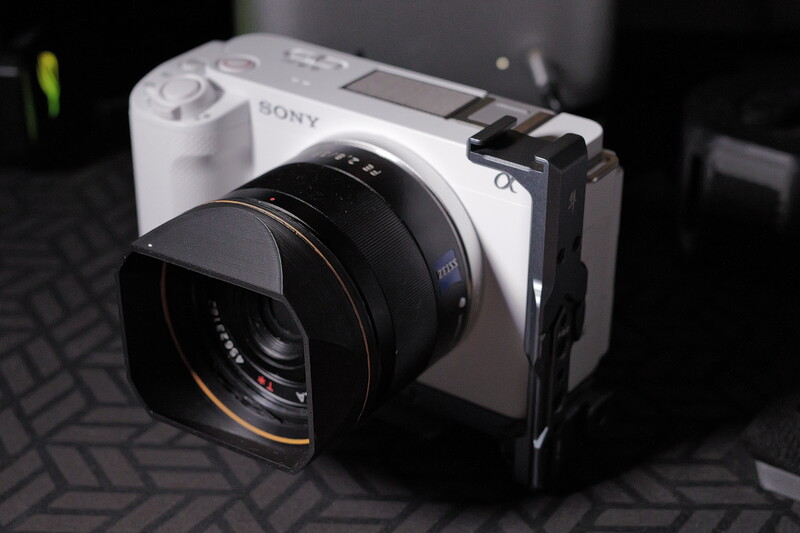 Sony mirrorless camera with black lens and L-bracket mounted on dark textured surface