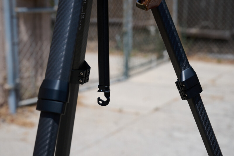 Close-up of tripod legs with metal clamps and cables against blurred urban background