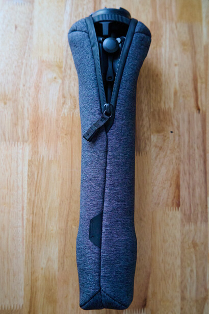 Blue knit sweater laid flat and rolled lengthwise on wooden floor