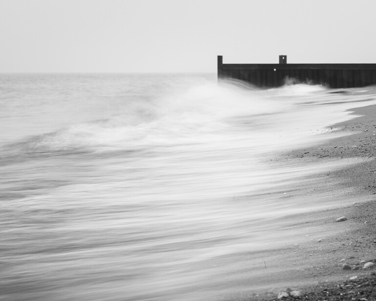 Black and white long exposure photo of waves washing over beach