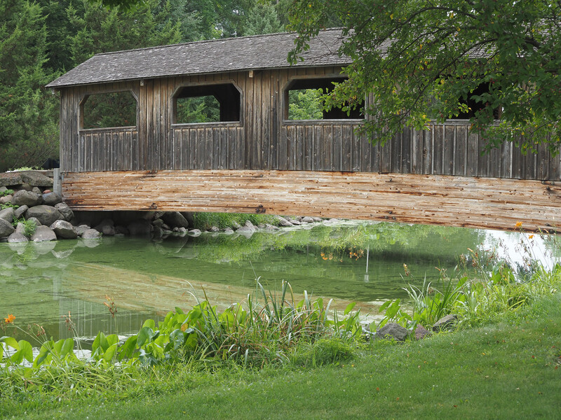 Photo of the side of a covered bridge and the near bank