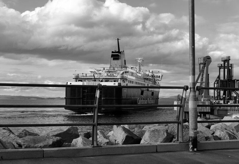 Large passenger ferry docked at industrial port facility in black and white