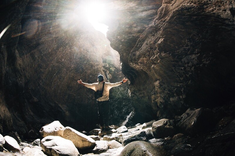 Chris Burkard standing with his back to the camera and with shining light overhead. 