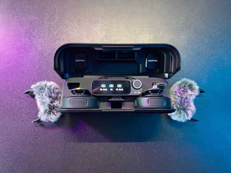 Portable audio device with dual fuzzy windscreens against gradient purple-to-blue backdrop