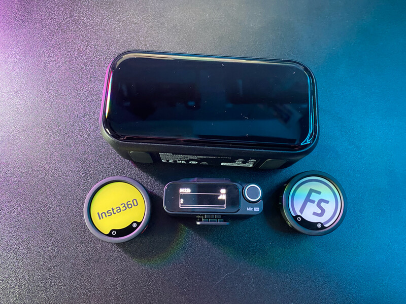Mobile phone with two round lens accessories labeled Insta360 and FS5 on gradient blue and pink background