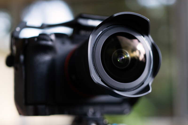 Black DSLR camera with wide-angle lens mounted, shot from front angle