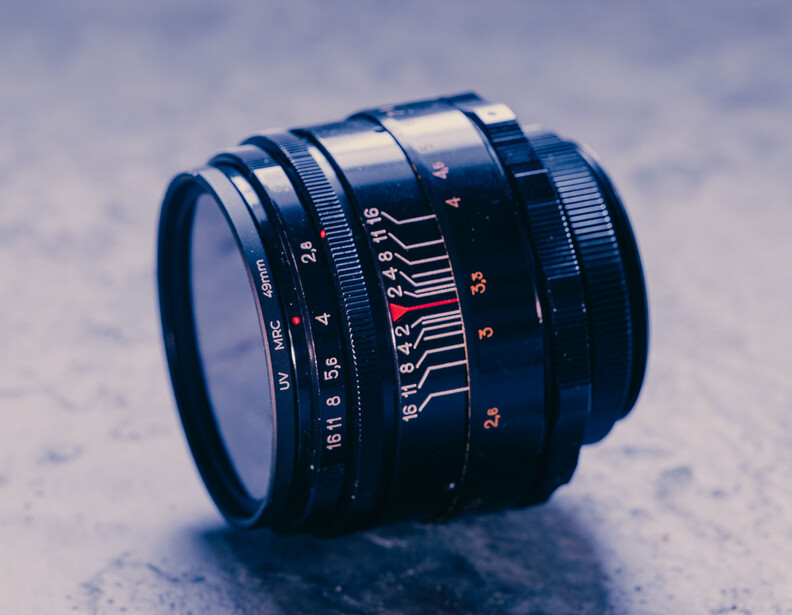 Vintage manual focus lens with depth of field markings and aperture scale on textured surface