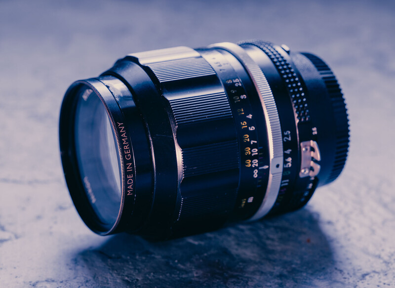 Vintage telephoto lens with blue and white barrel bands on textured surface