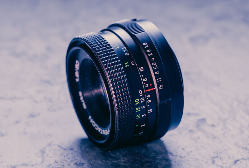 Vintage manual focus lens with aperture ring and distance scale markings on textured surface