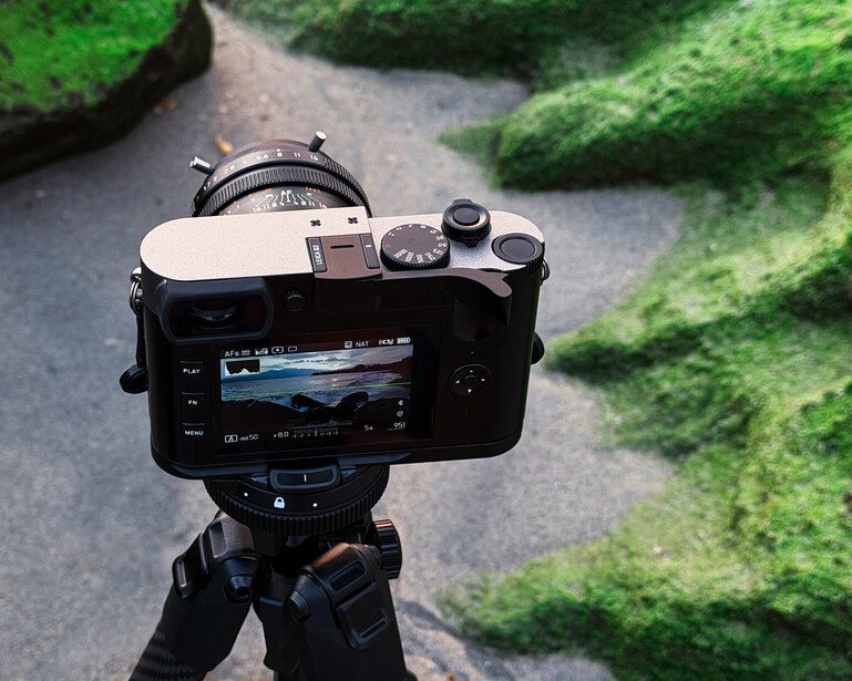 Mirrorless camera mounted on tripod displaying landscape footage on rear LCD screen