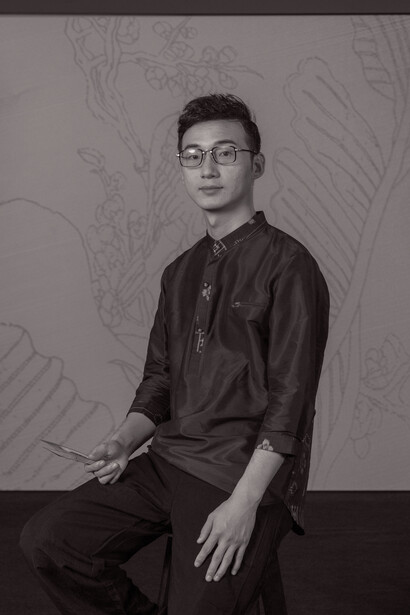 Portrait of a man wearing glasses and dark button-up shirt against patterned backdrop