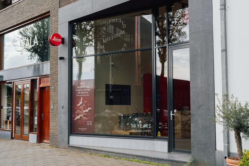 Modern storefront with large glass windows displaying red interior elements and a red circular logo above the entrance