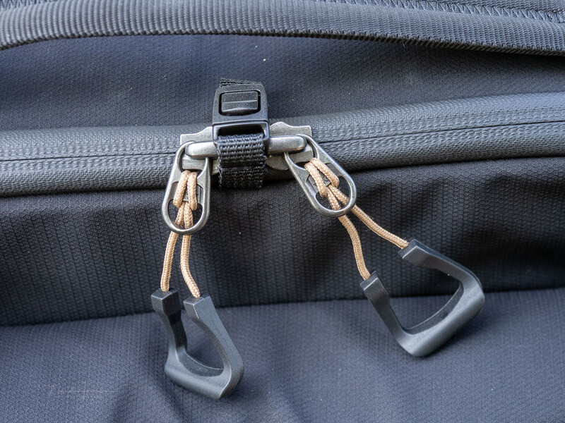 Dual carabiners with rope attached to luggage zipper pull on gray fabric