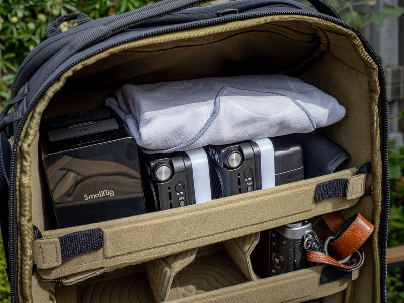 Camera backpack interior displaying organized photography gear including cameras, lenses, and accessories