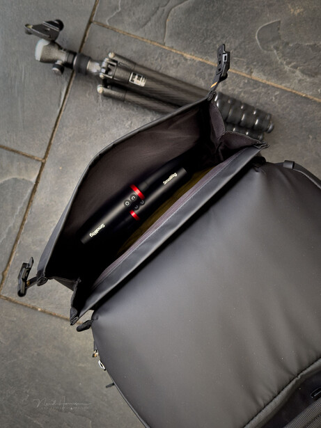 Photography gear laid out in a gray camera bag, including a syringe, lens, and other equipment
