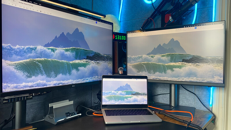 Multi-monitor workspace displaying seascape imagery with mountain and wave photography