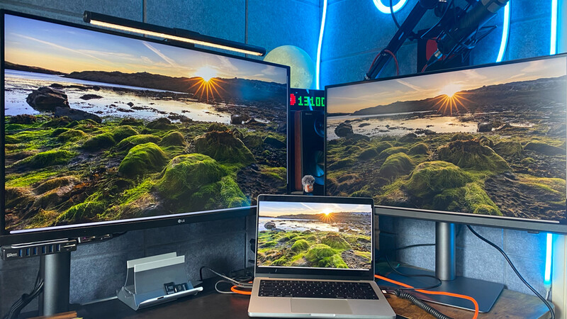 Multi-monitor photography workspace displaying coastal landscape images with moss-covered rocks and golden hour sunlight